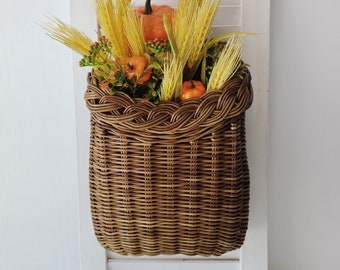 Basket on the door. Rounded flower basket. Wicker basket of motley color, decoration of the front door. Hanging basket on the door.