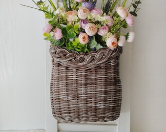 Basket on the door. Rounded flower basket. Wicker basket of motley color, decoration of the front door. Hanging basket on the door.