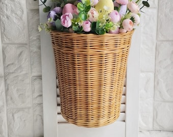 Basket on the door. Rounded flower basket. Wicker basket of motley color, decoration of the front door. Hanging basket on the door.