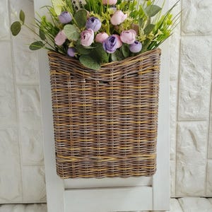 Basket on the door for flowers. Rectangular flat flower basket. Wicker basket in natural color, front door decoration. Hanging basket .