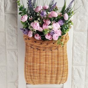 Basket on the door. Round flower basket. Brown wicker basket, front door decoration. Hanging basket on the door.