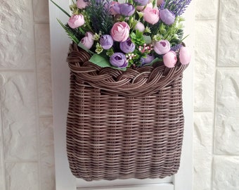 Basket on the door. Rounded flower basket. Wicker basket of motley color, decoration of the front door. Hanging basket on the door.