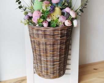 Basket on the door. Rounded flower basket. Wicker basket of motley color, decoration of the front door. Hanging basket on the door.