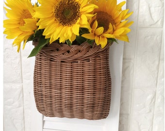 Basket on the door. Round flower basket. Brown wicker basket, front door decoration. Hanging basket on the door.