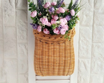 Basket on the door. Rounded flower basket. Wicker basket of motley color, decoration of the front door. Hanging basket on the door.