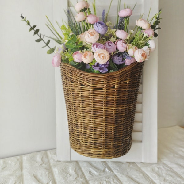 Basket on the door. Rounded flower basket. Wicker basket of motley color, decoration of the front door. Hanging basket on the door.