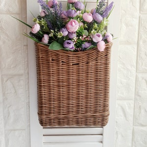 Mand op de deur voor bloemen. Rechthoekige platte bloemenmand. Rieten mand in natuurlijke kleur, decoratie op de voordeur. Hangmand.