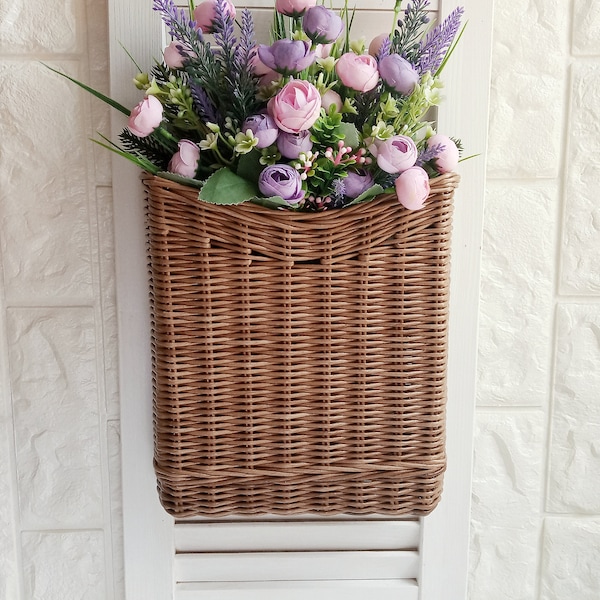 Basket on the door for flowers. Rectangular flat flower basket. Wicker basket in natural color, front door decoration. Hanging basket .