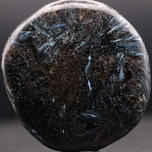 May include: A smooth, round, dark gray stone with blue and white streaks. The stone has a polished finish.