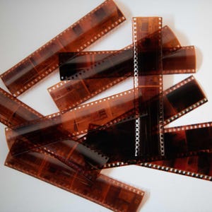 May include: A pile of brown and black 35mm film negatives.
