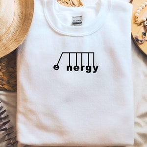 Könnte beinhalten: Weißes Sweatshirt mit einer schwarzen Grafik einer Schaukel mit dem Wort "Energie" darunter.