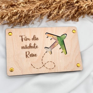 K&ouml;nnte beinhalten: Eine Holzkarten mit einem ausgeschnittenen Flugzeug und dem Text "F&uuml;r die n&auml;chste Reise".