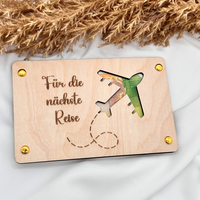 K&ouml;nnte beinhalten: Eine Holzkarten mit einem ausgeschnittenen Flugzeug und dem Text "F&uuml;r die n&auml;chste Reise".