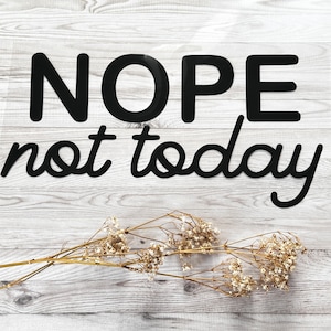 Könnte beinhalten: Schwarz-weißer Text auf Holzgrund liest "NOPE not today". Getrocknete Blumen befinden sich unten in der Mitte des Bildes.