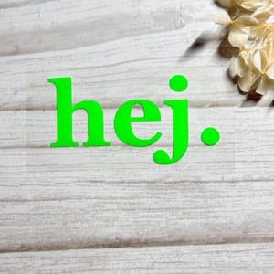 Könnte beinhalten: Ein grüner Vinyl-Aufkleber mit dem Wort "hej" in fetter Schrift.