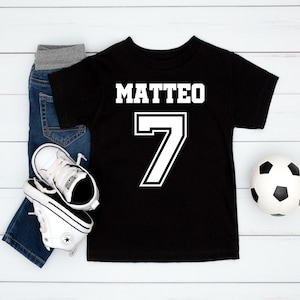 Könnte beinhalten: Schwarzes T-Shirt mit weißem Text "MATTEO" und der Nummer "7" in weißer Umrandung.