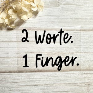 Könnte beinhalten: Ein transparenter Aufkleber mit schwarzem Text, der "2 Worte. 1 Finger." lautet.