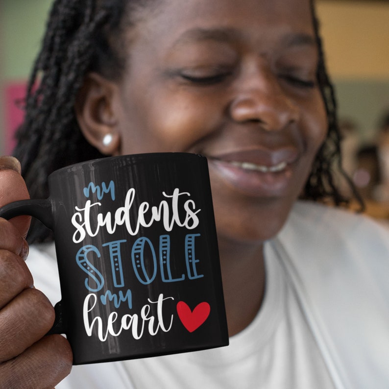 May include: Black coffee mug with white text that reads "my students stole my heart" with a red heart.