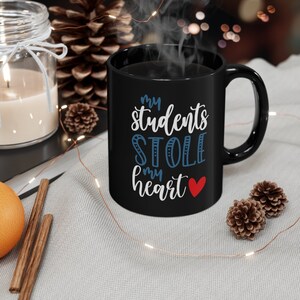 May include: Black coffee mug with white text that reads "My students stole my heart" with a red heart.