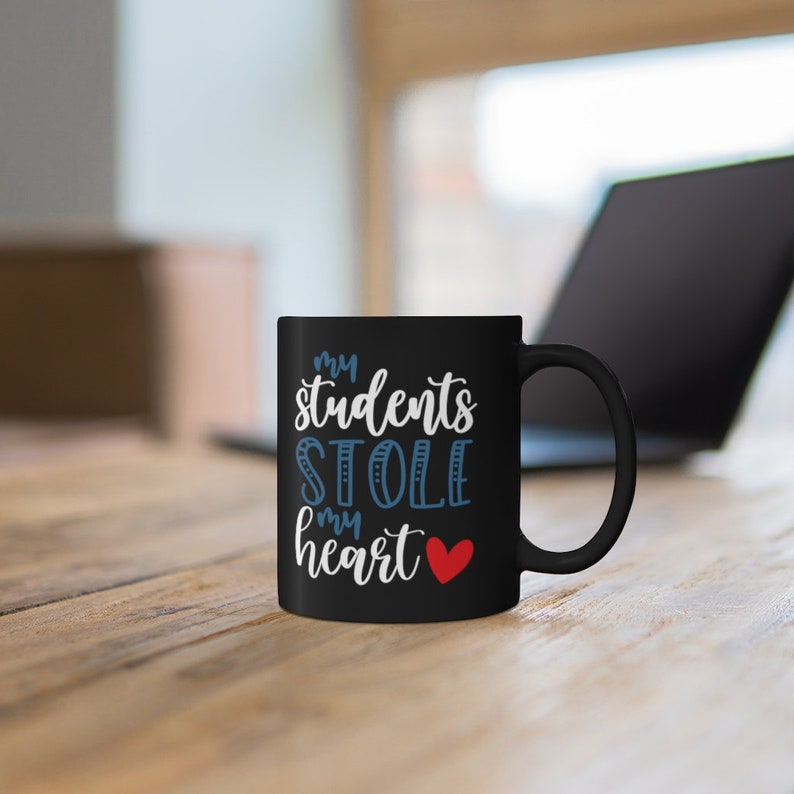 May include: Black ceramic coffee mug with the text "My students stole my heart" in white and blue lettering with a red heart.