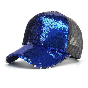 May include: A blue sequined baseball cap with a mesh back. The front of the cap and the bill are covered in shiny blue sequins. The back of the cap is made of a black mesh material.