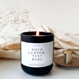 以下が含まれることがあります： 白いラベルに「Melou Candles」、「Your Custom Text Here」、「Handmade in Toronto | 100% Soy Wax」と書かれたガラスの瓶に入った黒いキャンドル。