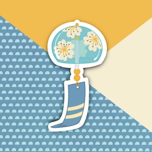 May include: A blue and white wind chime with a floral design. The chime has a round top and a long, pointed bottom. The top of the chime is decorated with white flowers on a blue background. The bottom of the chime is a solid blue color with a white stripe.