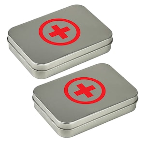 Peut inclure: Deux trousses de premiers soins en métal argenté avec un symbole de croix rouge sur le couvercle.