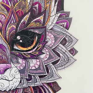 May include: A purple, gray, and white mandala-style jigsaw puzzle piece with intricate details. The piece features a large eye with a yellow iris and a black pupil.