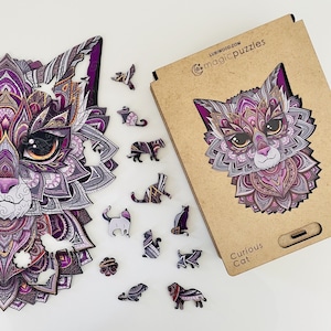 May include: A purple and gold intricate cat puzzle with a mandala design. The puzzle is made of wood and comes with a box that says "Curious Cat" and "Lubiwoood.com magicpuzzles".