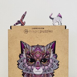 May include: A wooden puzzle featuring a detailed, colorful cat with purple, pink, and gold accents. The puzzle is made by Lubiwood.com and is called "magicpuzzles".