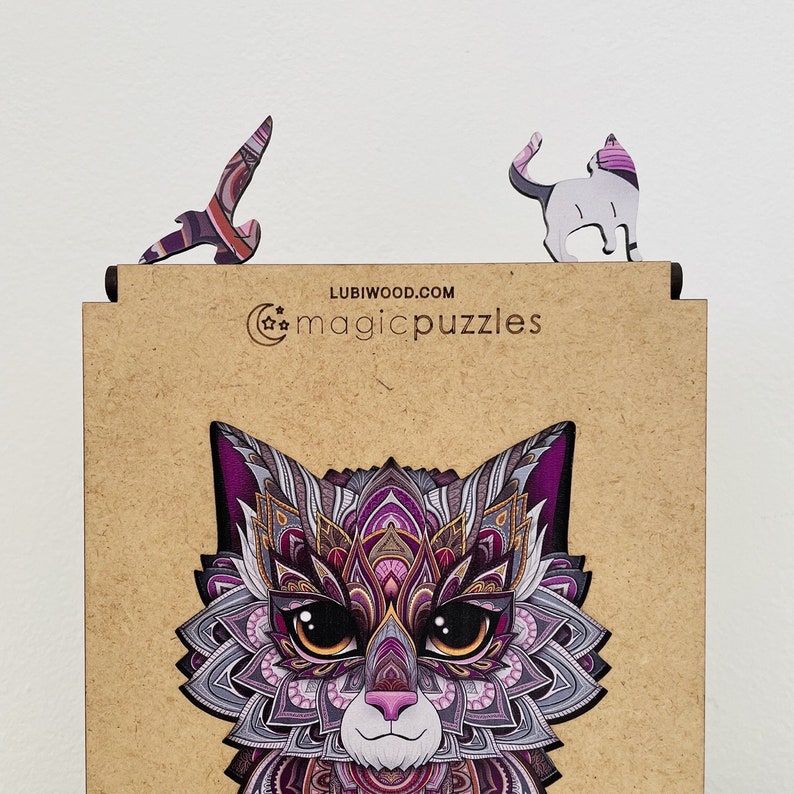 May include: A wooden puzzle featuring a detailed, colorful cat with purple, pink, and gold accents. The puzzle is made by Lubiwood.com and is called "magicpuzzles".