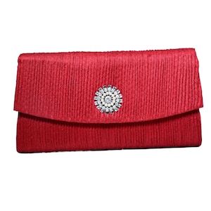May include: A red satin clutch with a silver and white rhinestone embellishment.