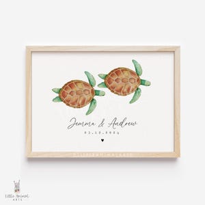 Puede incluir: Impresión en acuarela enmarcada con dos tortugas marinas, con caparazones marrones y aletas verdes. La impresión incluye los nombres "Jemma & Andrew", la fecha "03.12.2024" y un pequeño corazón. El marco es de madera clara.