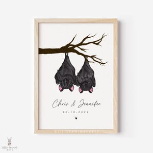 May include: A framed print featuring two black bats hanging upside down from a brown branch. The bats have pink ears. The print includes the names "Chris & Jennifer" and the date "18.10.2026".