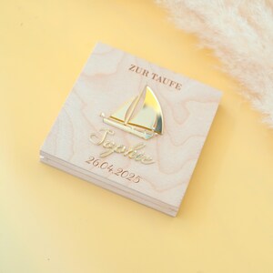 May include: A wooden box with a gold sailboat and the name "Sophie" engraved on it. The box also has the text "Zur Taufe" and the date "26.04.2025" engraved on it.
