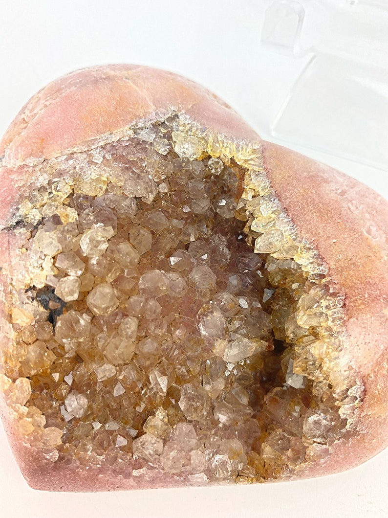 May include: A heart-shaped geode with a pink exterior and a cavity filled with clear quartz crystals.