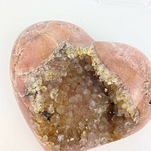 May include: A heart-shaped geode with a pink exterior and a hollow interior filled with clear quartz crystals.