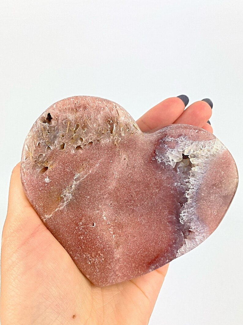 May include: A heart-shaped pink and white agate crystal with a natural druzy formation. The crystal is polished and has a smooth surface.