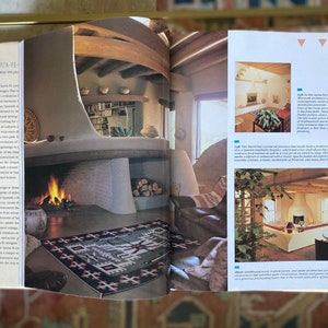May include: A living room with a large fireplace and a rug with a southwestern design. The room has a beamed ceiling and a large window. The text in the image reads "Left: This living room, Westwood Architects created a contemporary space with a monumental fireplace, a concealed television, and a large rug.  The room has a comfortable, triangle-shaped banquette and a low, deep sofa to lean toward.  There is a deep, soft bed that crowns the seating platform, and handsome plantings."