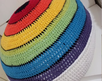 May include: A round, crocheted pouf in a vibrant rainbow pattern. The design features concentric circles of red, orange, yellow, green, blue, purple, and white. The handmade pouf is a decorative and functional home decor item.