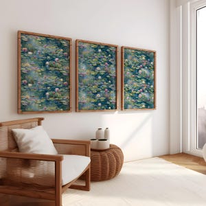Op de afbeelding: Drie ingelijste wandkunstwerken met een aquarel schilderij van een vijver met waterlelies en bloemen in tinten blauw, groen en roze. De lijsten zijn gemaakt van lichtbruin hout. Het kunstwerk wordt tentoongesteld in een lichte kamer met een houten stoel en een geweven bijzettafel.