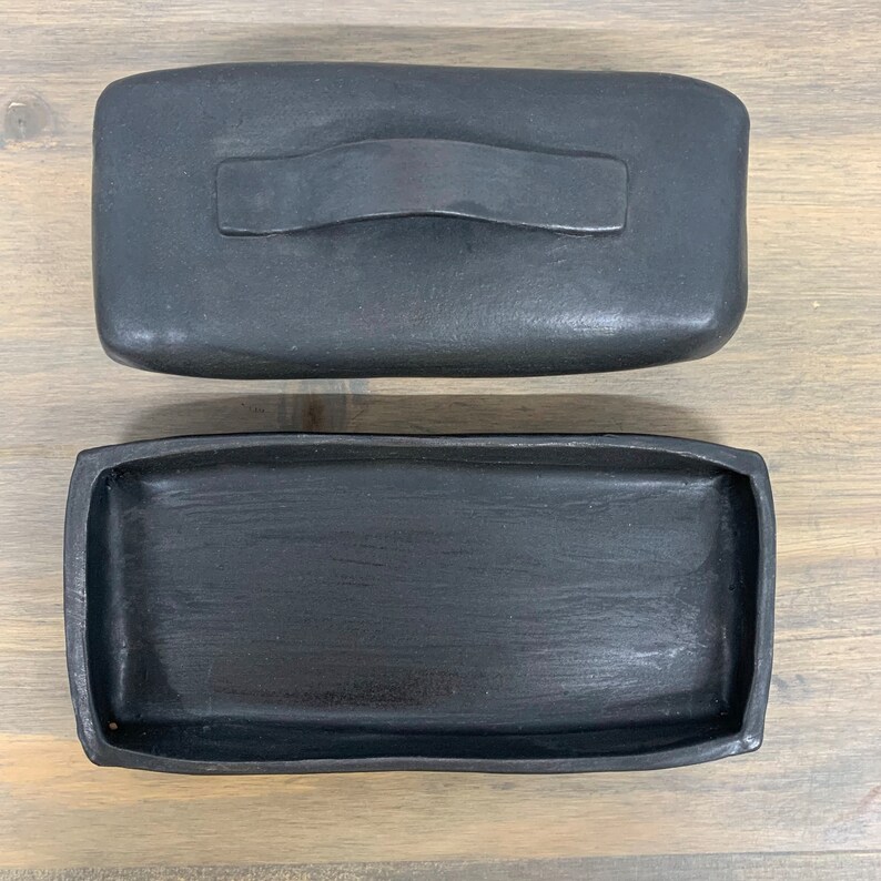 May include: A black rectangular ceramic tray with a matching lid. The lid has a handle.