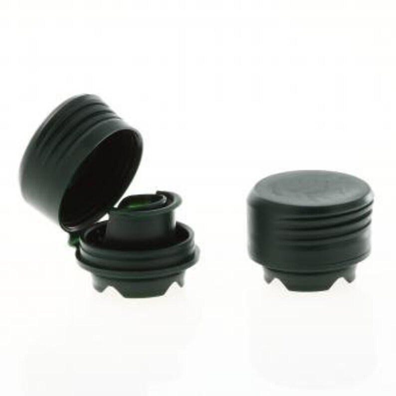 Puede incluir: Dos tapones de botella de pl&aacute;stico negro con un dise&ntilde;o acanalado. Un tap&oacute;n est&aacute; abierto, revelando un mecanismo interno verde.