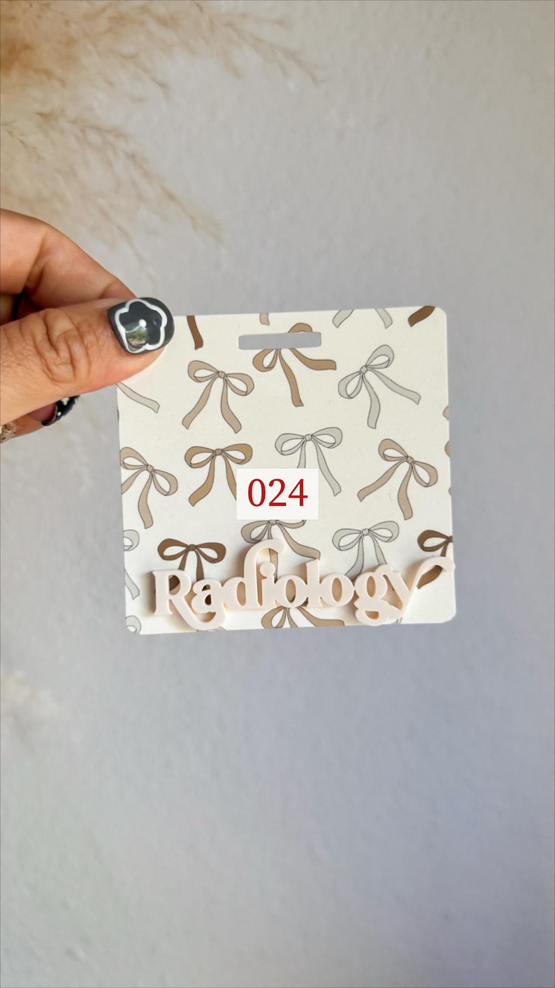 May include: A badge with a bow pattern in shades of brown and gray. The badge has the word "Radiology" in a light color and the number "024" in a red box.