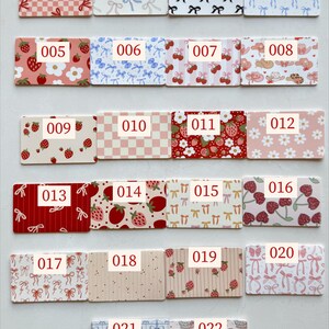 May include: A collection of 22 rectangular cards with various patterns and the numbers 001-022 printed on them. Designs include bows, strawberries, cherries, and floral patterns in colors like red, pink, and blue.