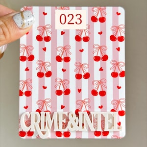 May include: A rectangular, white and pink striped item with a cherry pattern and the text "CRIME & INTEL". The number "023" is in a white box. The cherries are red with a red bow.