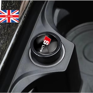 May include: A black car cigarette lighter adapter with a red and white "S line" logo.