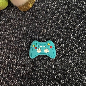 May include: A blue plastic toy video game controller with green, yellow, and red buttons.