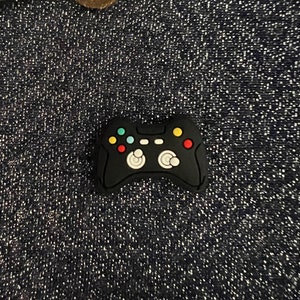 May include: Black rubber game controller charm with colorful buttons.